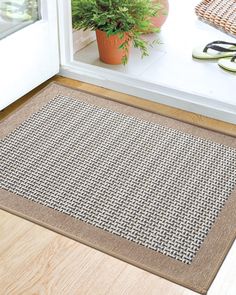 a close up of a door mat on the ground near a potted plant and pair of glasses