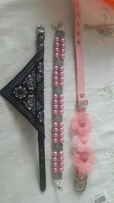 two pink and silver items are on a white sheet next to a black triangle with beads