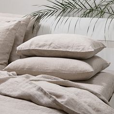 three pillows stacked on top of each other in front of a bed with white sheets