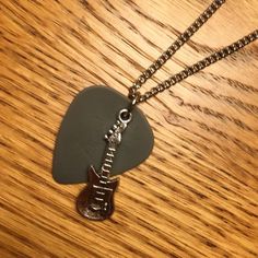 an electric guitar pickle on a wooden table with a metal chain attached to it