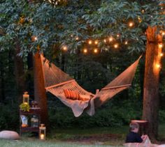 a person laying in a hammock with lights strung from the trees