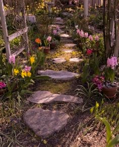 a garden with lots of flowers and rocks in the grass near a wooden trellis