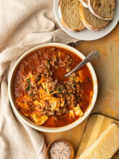 a bowl of pasta soup with bread on the side