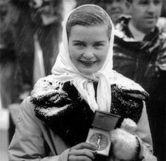 an old black and white photo of a woman holding a teddy bear in the snow