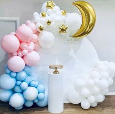 balloons, stars and moon are on display in front of a white pillar with a gold crescent