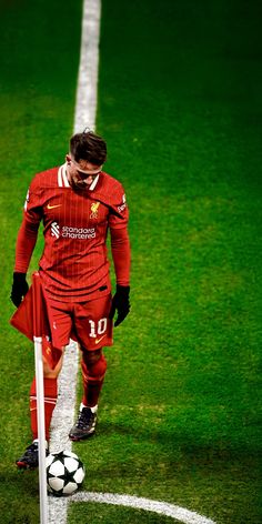 a man in red uniform standing next to a soccer ball