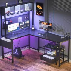 a computer desk with purple lighting in an office space, next to a wall mounted monitor