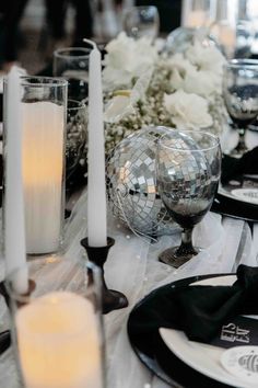 the table is set with black and white plates, silverware, candles and flowers