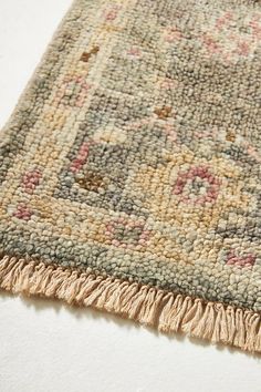 an area rug with fringes on top of it and a white wall in the background