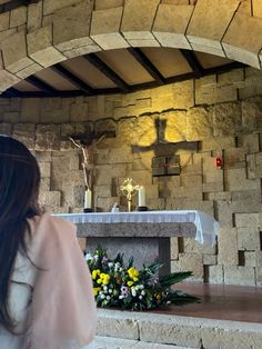 a woman standing in front of a stone alter with flowers and candles on the altar