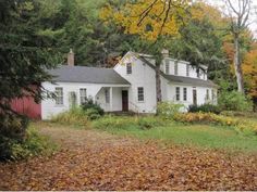 a white house surrounded by trees and leaves