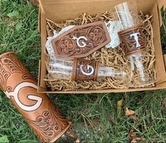 an open box with some items in it sitting on the grass next to a pair of cowboy boots