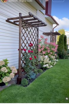 an outdoor garden with flowers and plants in the foreground, next to a house