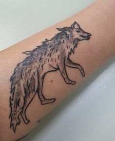 a black and grey wolf tattoo on the arm