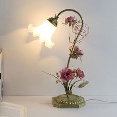 a lamp that is on top of a table next to a book and some flowers