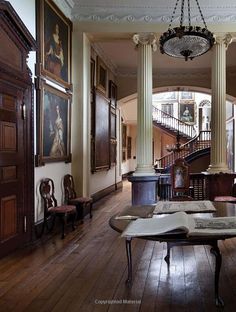 an open book sitting on top of a wooden table in a room filled with paintings