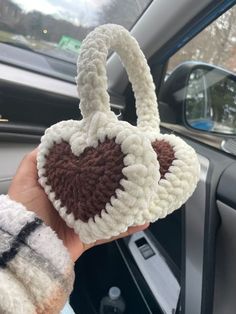 someone is holding up a crocheted heart in their hand while inside the car