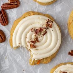 several cookies with white frosting and pecans scattered around them