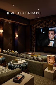 a home theater with two couches and a large screen on the wall above it