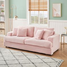 a pink couch sitting in a living room next to a window