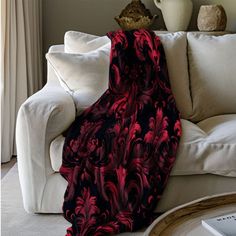 a red and black blanket sitting on top of a white couch