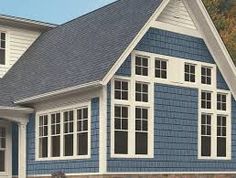 a blue house with white windows and shingles on the roof is shown in this image