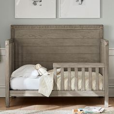 a baby crib with two pictures on the wall above it