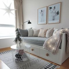 a living room filled with furniture and christmas decorations on top of a wooden floor next to a window