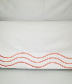 an orange and white pillow on top of a bed