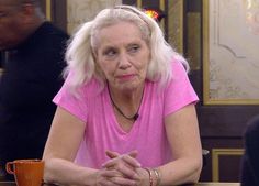 an older woman sitting at a table with a cup