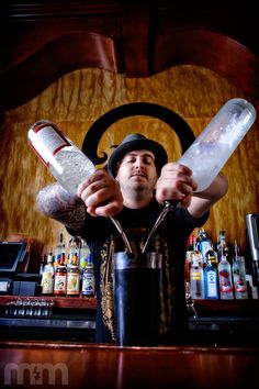 a man holding two empty bottles behind a bar