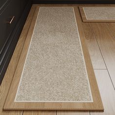 two beige rugs on the floor in a kitchen with wood floors and cabinets behind them