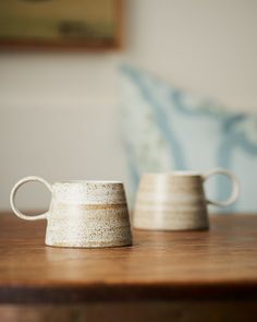 two white cups sitting on top of a wooden table