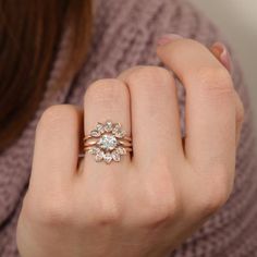 a woman's hand wearing a gold ring with three flowers on the band and a diamond in the middle