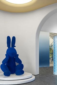 a blue rabbit statue sitting on top of a white pedestal in front of a doorway