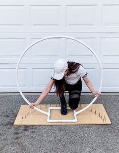 a woman sitting on top of a wooden board in front of a white garage door