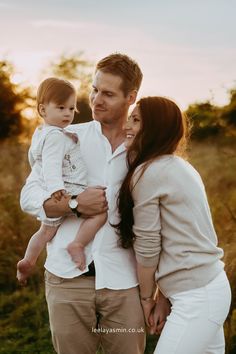 a man and woman holding a baby in their arms