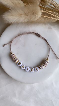 the bride bracelet is shown on a white plate next to some dried grass and feathers