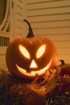 a carved pumpkin sitting on the ground with its eyes glowing in front of it's face