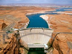 an aerial view of a large dam with water in the middle and brown cliffs surrounding it