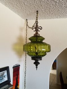 a green glass chandelier hanging from the ceiling in a room with white walls