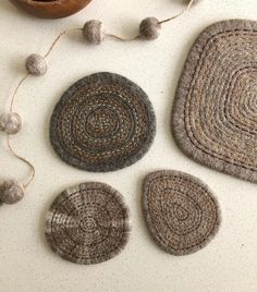 three crocheted coasters and a pot holder on a white table with yarn balls