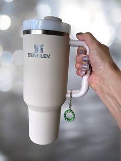 a hand holding a coffee cup with a key chain attached to it's side