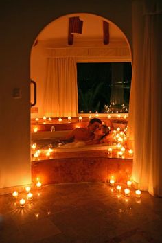 a man and woman are in the bathtub with candles