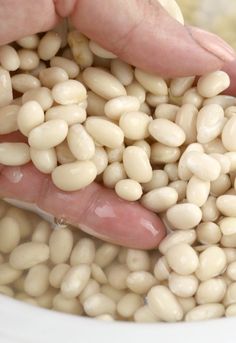 a person is scooping beans into a bowl with their hand to eat the food