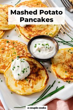 mashed potato pancakes with sour cream and chives on a white plate next to a fork