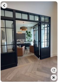 an open glass door leading to a living room and dining area with wood flooring