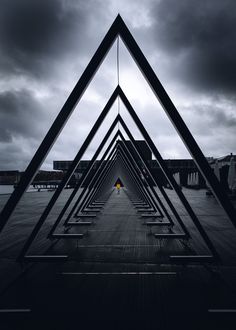 a person standing in the middle of a long row of metal structures on top of a wooden floor