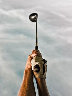 a man holding a metal object in his hand with cloudy sky behind him and blue skies above