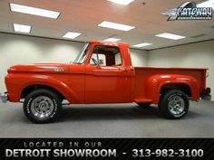 an old red pickup truck is parked in a showroom with the words detroit showroom on it's side